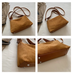 Détail du sac polochon en daim caramel avec clous en métal et base en cuir lisse