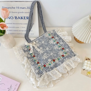 Close-up of floral embroidery and layered lace edges on a plaid canvas tote bag