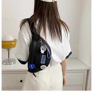 Detail of black sporty crossbody bag with astronaut pendant and fashion badges for women