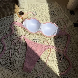 Detail of pink shell bikini top with crochet fringe and textured fabric on beach mat