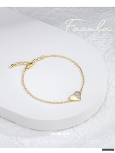 Detailed macro of a gold heart charm bracelet featuring half-set sparkling zircons