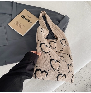 Vue détaillée du sac cabas beige tricoté avec motifs de cœurs noirs sur une surface texturée