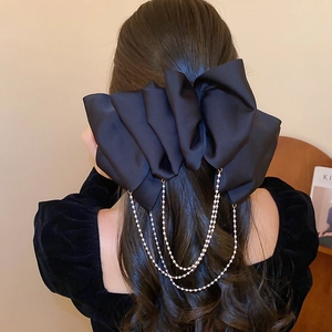 Detail of elegant black satin bow hair clip featuring dangling pearl tassel chains