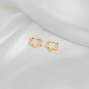 Detailed close-up of golden star hoop earrings with bamboo texture on white silk fabric