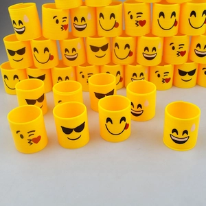 Mini yellow spring toys with various emoji faces scattered on a clean grey background