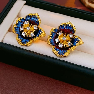 Detail of vintage flower earrings with blue enamel petals and sparkling center crystals