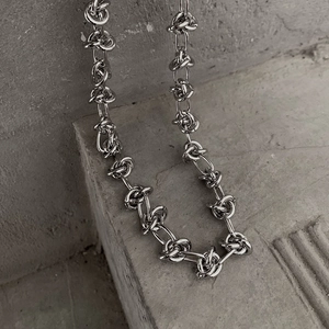 Detail of silver interlocking knot chain necklace with industrial style metal finish