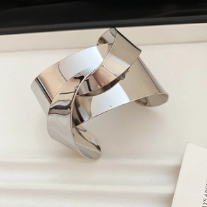 Macro view of high-polished silver crossover cuff bracelet with metallic mirror finish