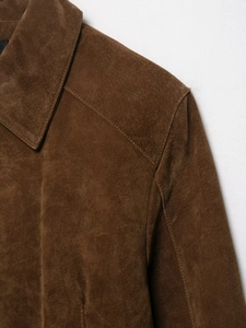 Détail d'une veste en daim marron montrant des coutures fines et une texture douce