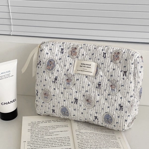 Quilted bear pattern makeup bag with blue floral print and zipper closure on white desk