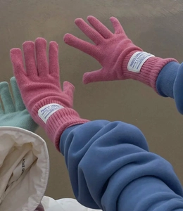 Detalle de guantes de lana rosa con puños acanalados y etiquetas tejidas de invierno