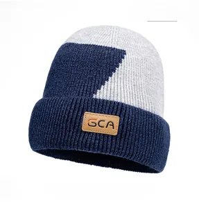 Dettaglio del berretto in maglia blu e grigio con toppa in pelle marrone logo GCA