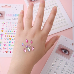 Detailed macro view of 3D facial gem stickers and rhinestones on skin with pink background