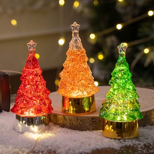Three LED crystal Christmas trees with star tops on wooden slices and fake snow