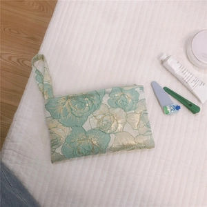 Detail of light green rose jacquard fabric pouch with golden thread and wrist strap
