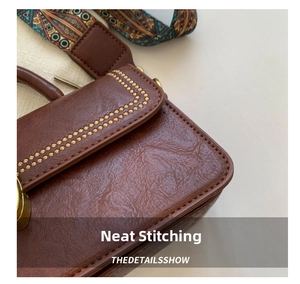 Detail of retro brown leather bag featuring contrast stitching and jacquard strap