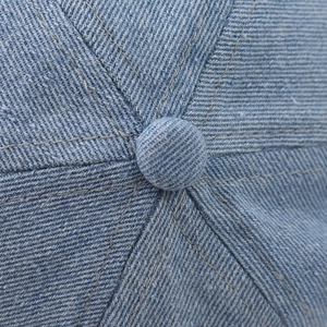 Detail of light blue washed denim hat crown with reinforced top button and stitching
