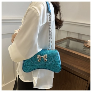 Close-up of blue sequin crescent bag with metallic bow and silver chain strap