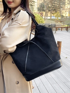 Large black suede and leather tote bag styled with a beige trench coat for a casual look