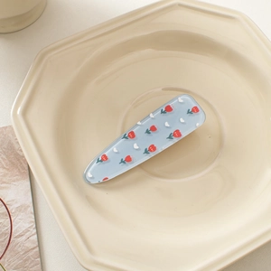 Detailed view of a blue acrylic hair clip featuring cute red tulip patterns and white flowers