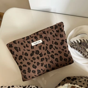 Trousse à maquillage vintage en velours côtelé léopard avec étiquette sur table blanche