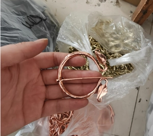 Detail of rose gold metal viking brooch featuring round leaf design and sharp pin fastener