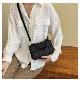 Detail of black quilted chain crossbody bag with glitter texture and acrylic strap