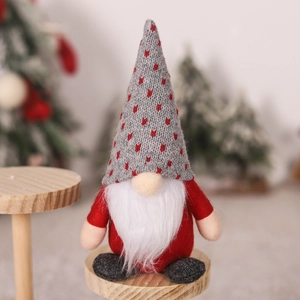 Dettaglio di uno gnomo natalizio con cappello in maglia grigia su base di legno