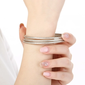 Detail of three-piece set of brushed silver stainless steel bangles worn by a model