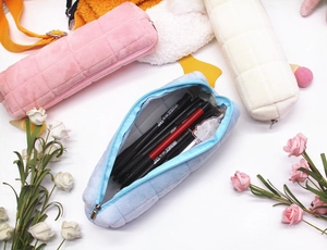 Detailed close-up of soft plush quilted pencil cases in pink, blue, and cream colors
