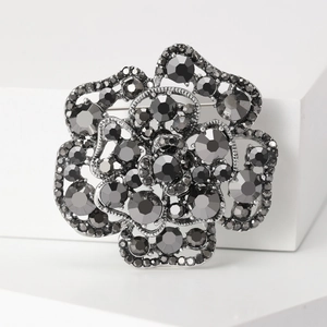 Close-up of vintage 3D rose brooch featuring grey rhinestones and dark metal finish