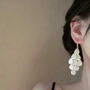 Close-up of elegant pearl-white multilayer teardrop earrings worn by a model
