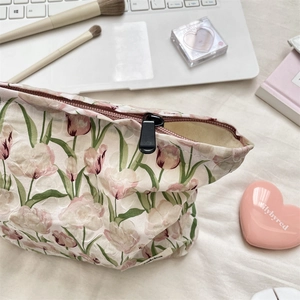 Détail d'une trousse à maquillage tulipe en tissu texturé avec fermeture éclair sur fond