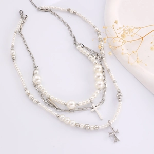 Close-up of pearl necklace with silver cross charms and butterfly tassels