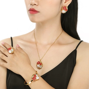 Detail of a luxury gold jewelry set with pearls and red flowers worn by a model