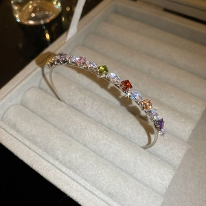 Macro detail of silver open bangle featuring colorful gradient zircon gemstones and crystals