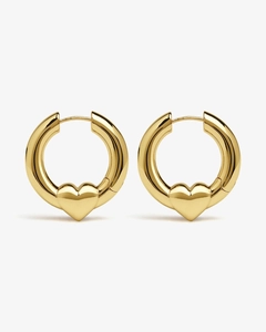 Detailed close-up of chunky gold hoop earrings with polished heart charms on gray background