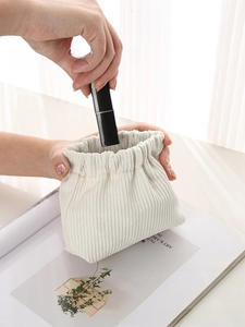 Close-up of cream corduroy storage pouch being opened for small cosmetics like lipstick