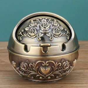 Close-up of vintage bronze spherical ashtray with rose reliefs and three cigarette slots