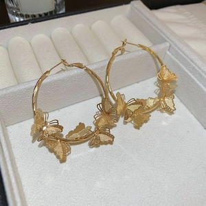 Detail of gold butterfly hoop earrings with matte textured charms on a jewelry box