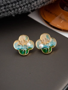 Macro detail of oil painting style clover earring with enamel flower and pearl inlay
