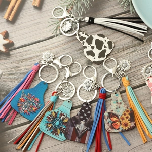 Detailed view of bohemian western cow-tag keychains with sunflowers and suede tassels