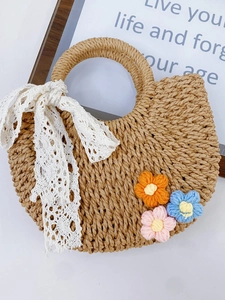 Mini-Strohbeuteltasche mit Spitzenschleife und Häkelblumen auf weißer Oberfläche