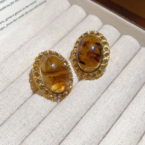 Close-up of amber resin oval earrings with sparkling crystal halo in a velvet box