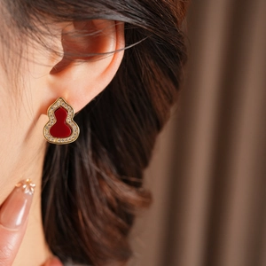 Nahaufnahme vergoldeter Flaschenkürbis-Ohrringe mit rotem Inlay und Kristallakzenten