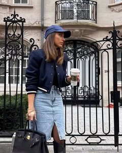 Chic street style featuring a navy varsity jacket and washed denim maxi skirt with slit