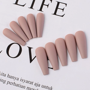 Close-up of matte nude pink long coffin press-on nails displayed on a magazine page