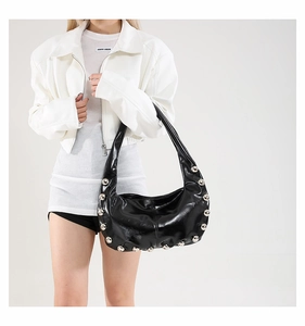 Detail view of glossy black faux leather hobo bag with large metallic studs and silver rivets
