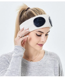 Close-up of a white knit headband featuring decorative black goggles for a winter look