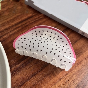 Detail of acrylic dragon fruit hair claw clip featuring pink edges and black seed dots